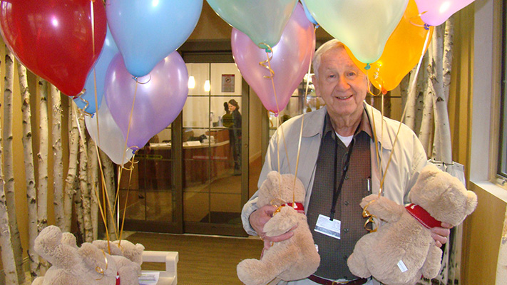 Volunteer with balloons and teddy bears